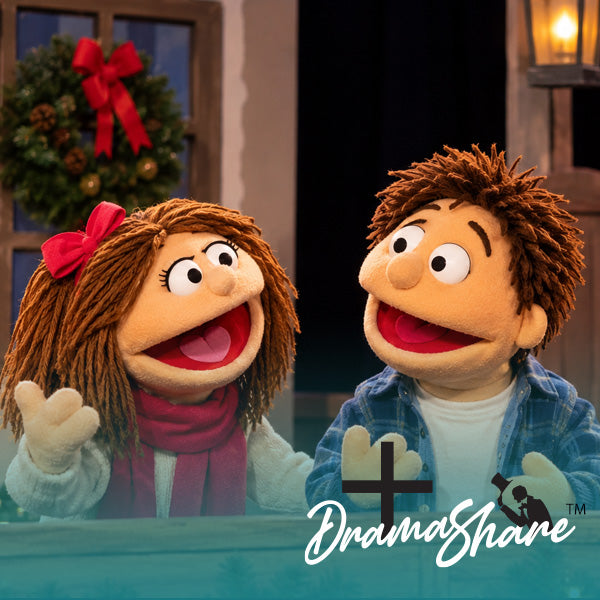 Two Christmas-themed puppet characters, a girl with brown yarn hair and a red bow/scarf and a boy with brown yarn hair in a blue plaid shirt, sitting at a table with a holiday wreath in the background. A 'DramaShare' logo is visible in the bottom right corner.