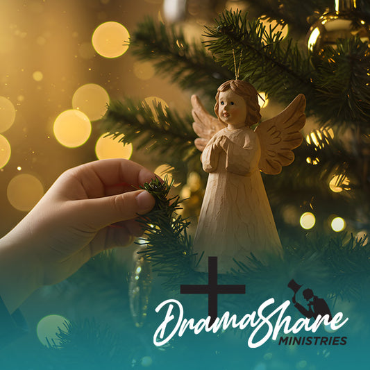 Hand placing an angel ornament on a Christmas tree with blurred lights in the background.