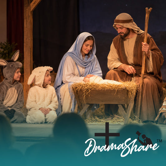A theatrical Christmas nativity scene with three costumed performers: a donkey, a sheep, and Mary, with Joseph holding a staff beside a baby in a manger. A large teal overlay at the bottom reads 'DramaShare' with a black cross icon.