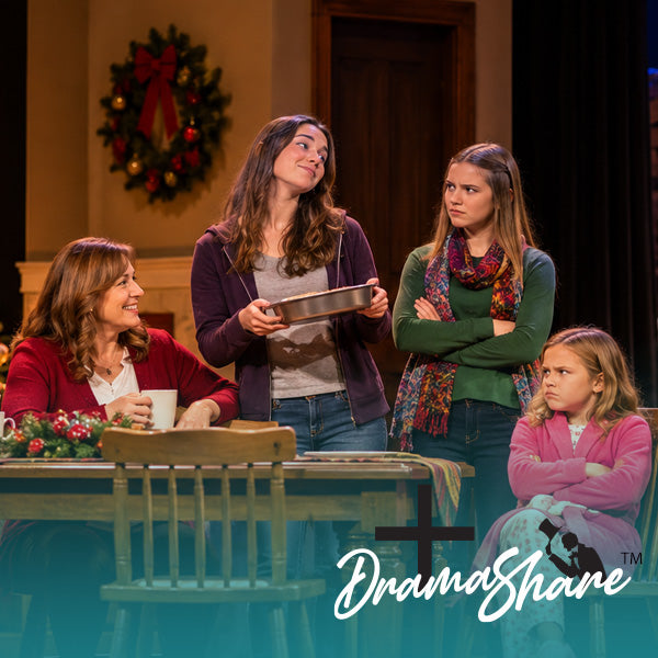 A theatrical stage scene with four people gathered around a table. One woman stands holding a tablet, one woman sits at the table, and two girls stand and sit nearby.